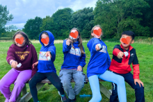 Five children pictured in a field with trees in the background, enjoying the activities.