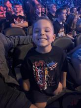 Oliver is pictured smiling and wearing a wrestling T shirt